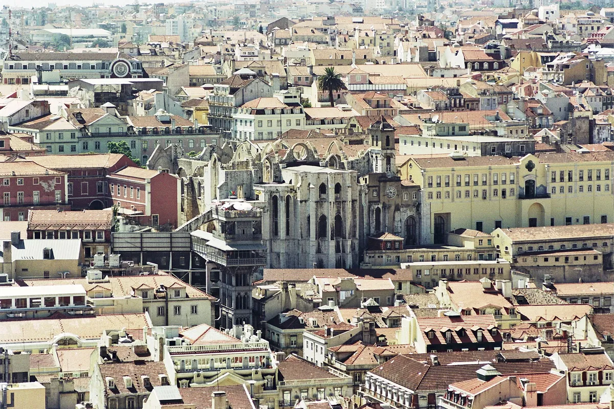 Terracotta roofs of Lisbon's old centre with the roofless Gothic walls of the Carmo convent church in the middle distance.